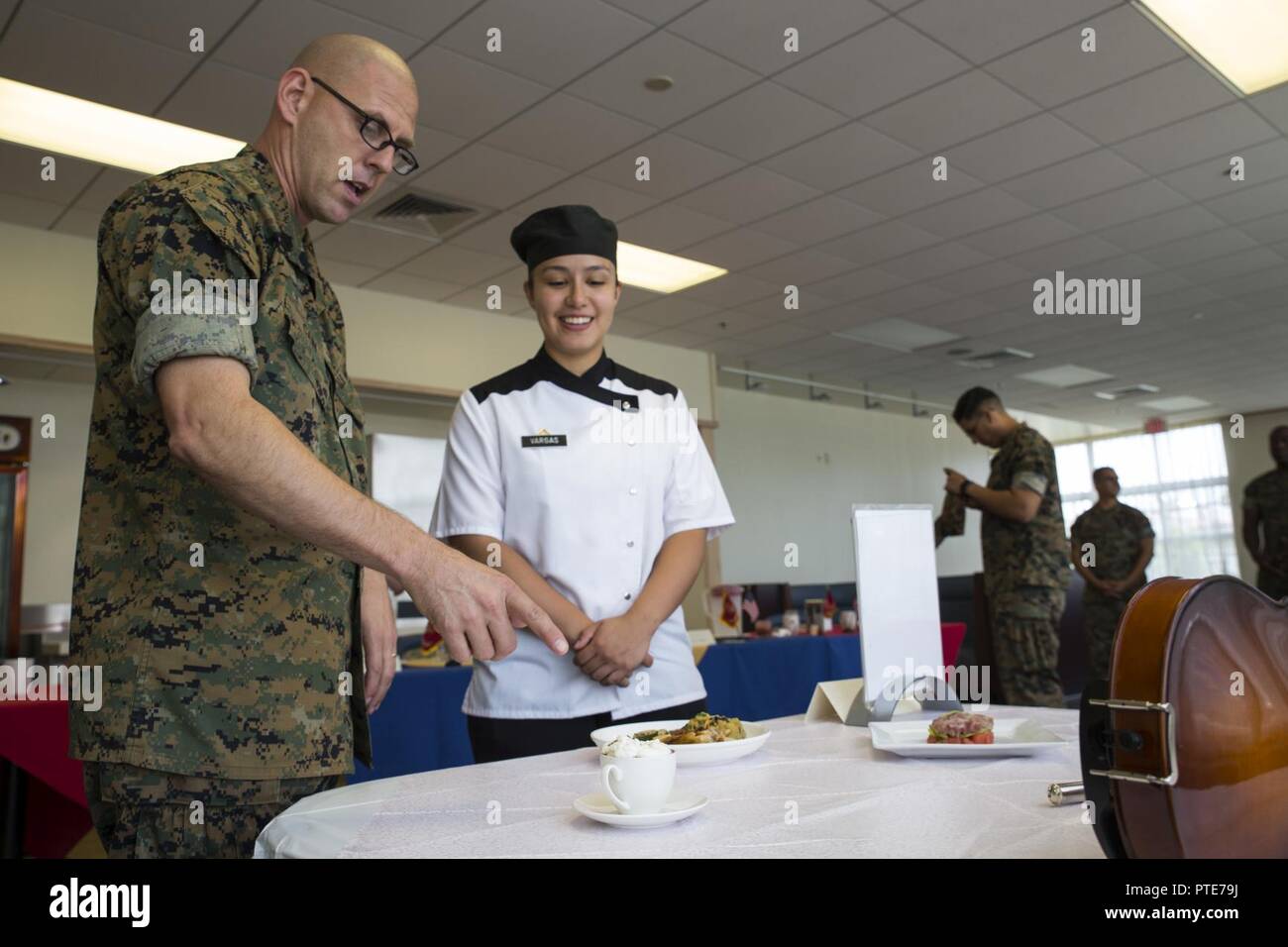 U.S. Marine Corps Sgt. Maj. Jason R. Cain, left, sergeant major of Headquarters and Headquarters Squadron (H&HS), talks to Lance Cpl. Erika Vargas, right, a food service specialist with, about the dark chocolate mousse she prepared for the Food Service Specialist of the Quarter competition at Marine Corps Air Station (MCAS) Iwakuni, Japan, July 13, 2017. The event prepared Marines for a larger competition July 226-27 in Okinawa. Vargas took first place, surpassing her placement last quarter. Stock Photo