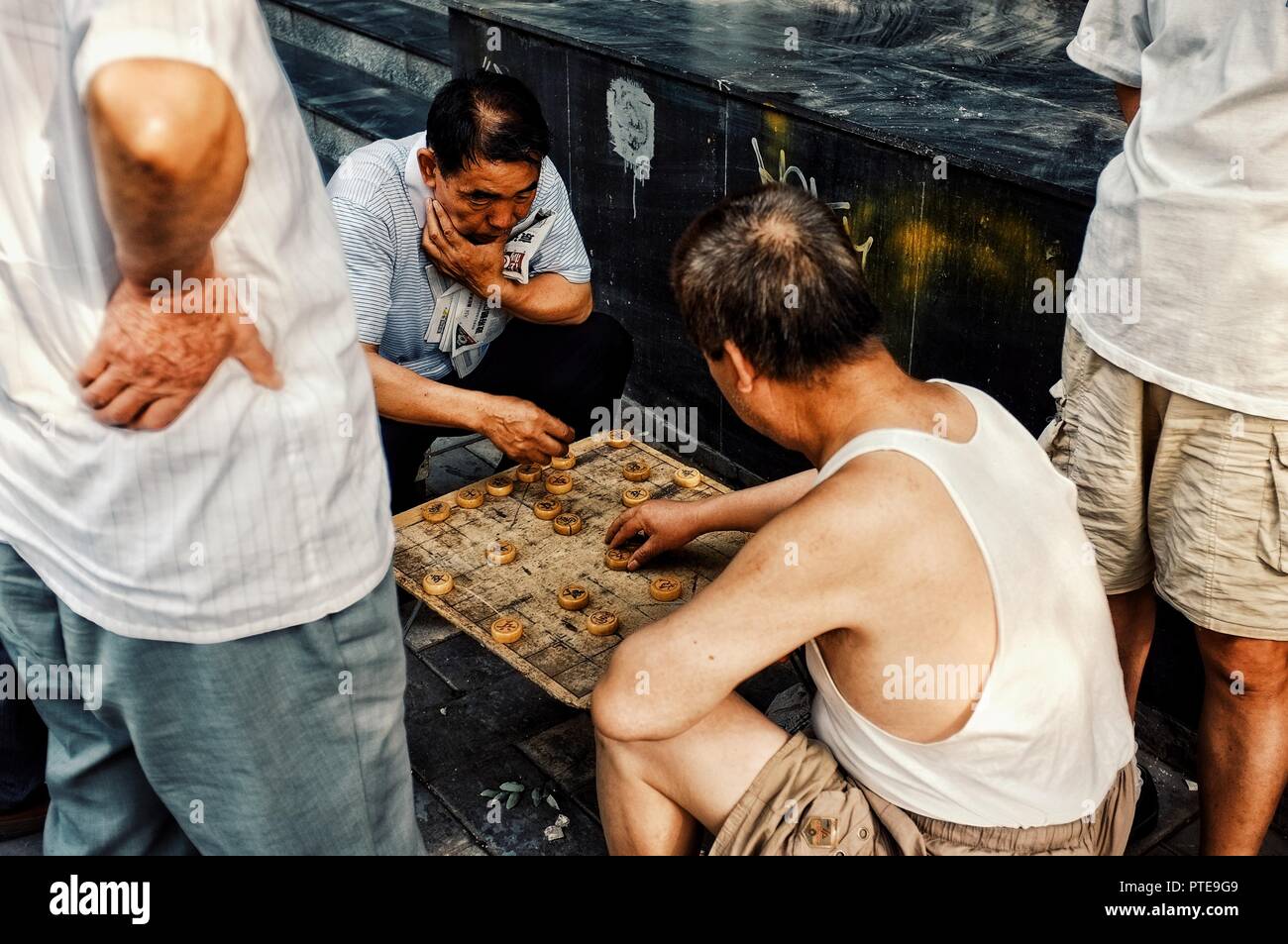 Beijing / China - JUN 24 2011: people playing typical xiangqi chinese chess on the street in a traditional chinese city hutong Stock Photo