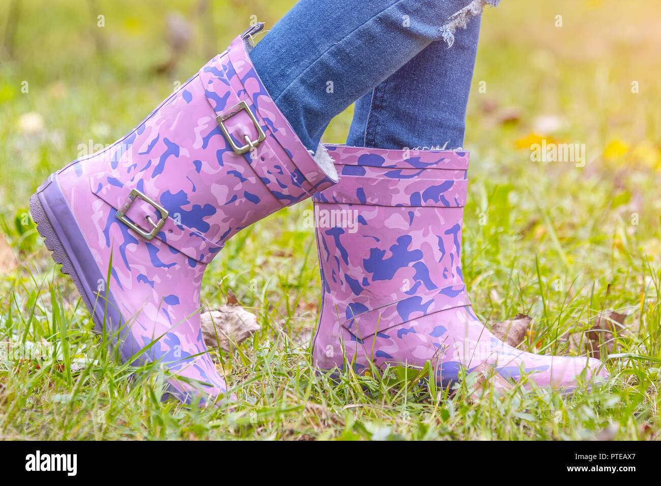 children's feet in rubber boots on yellowed dry grass in autumn Stock ...