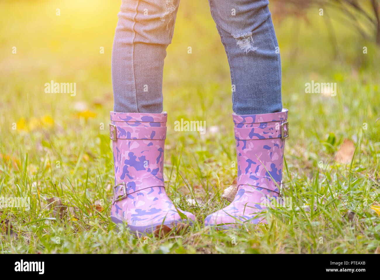 children's feet in rubber boots on yellowed dry grass in autumn Stock ...