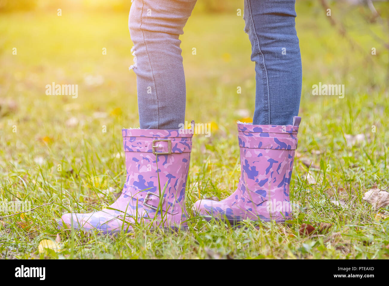 children's feet in rubber boots on yellowed dry grass in autumn Stock ...