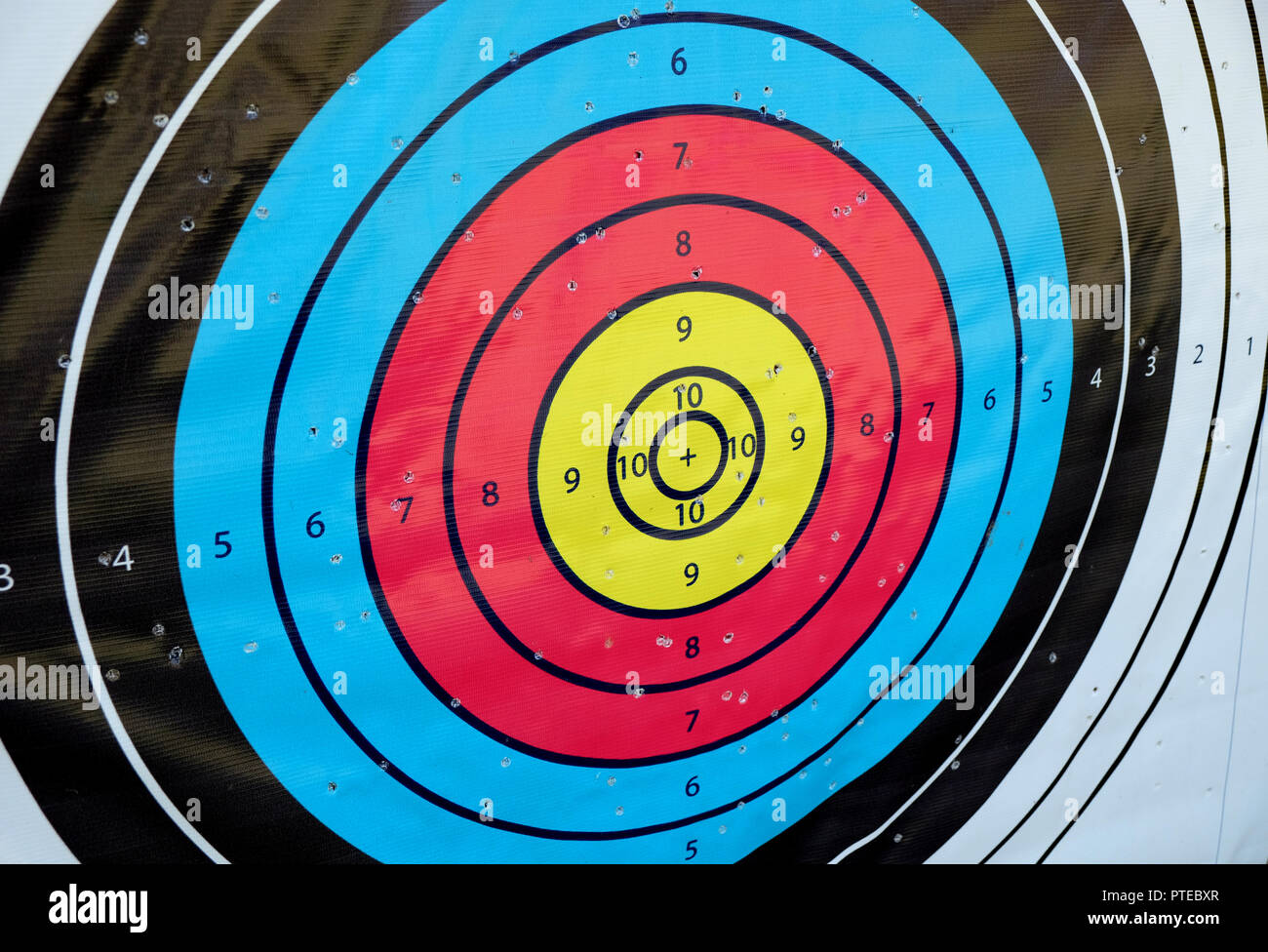 Archery target close up with many arrow holes in gold red blue and black Stock Photo