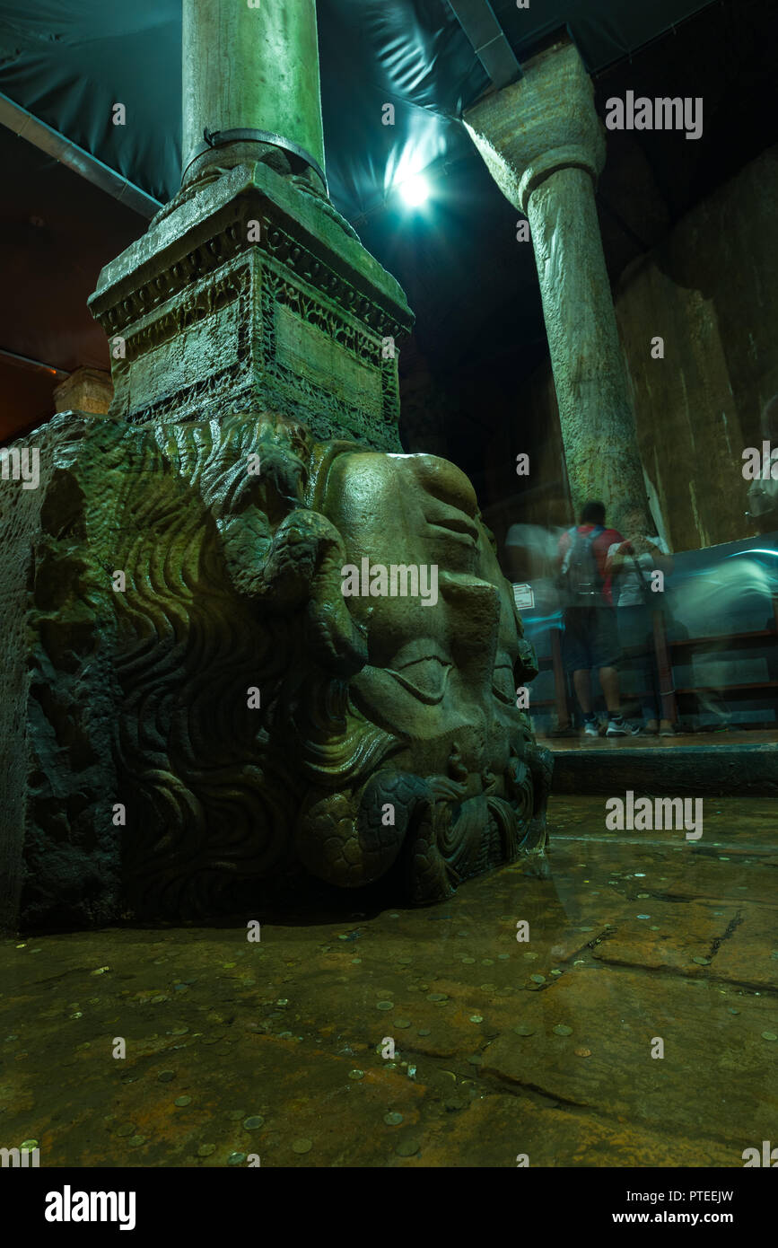 Tourists stand around one of the ancient Medusa head column pedestals within the Roman Basilica Cistern or Yerebatan Sarnıcı, Istanbul, Turkey Stock Photo