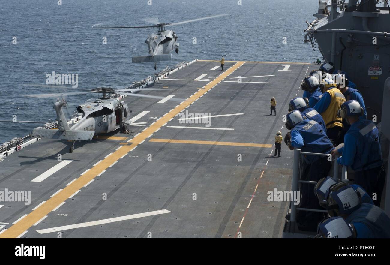 ATLANTIC OCEAN (July 12, 2017) Two MH-60S Sea Hawk Helicopters take off during flight deck qualifications as Sailors watch aboard the amphibious assault ship USS Wasp (LHD 1). Wasp is currently underway acquiring certifications in preparation for their upcoming homeport shift to Sasebo, Japan where they are slated to relieve the USS Bonhomme Richard (LHD 6) in the 7th Fleet area of operations. Stock Photo