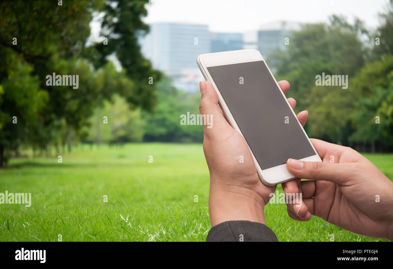 Woman holding white smart phone with blank desktop screen in outdoor with blur green mountains background Stock Photo