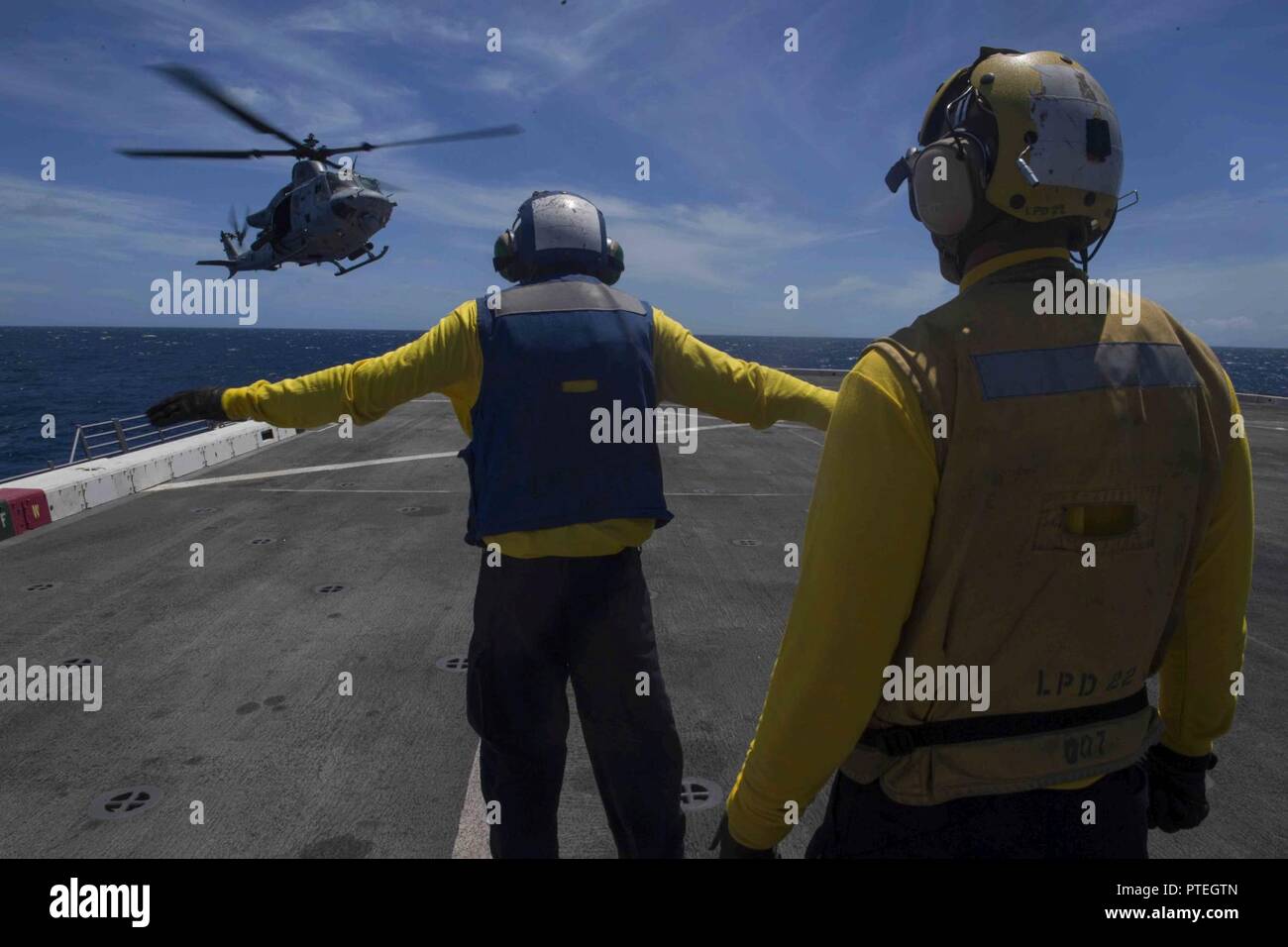 PACIFIC OCEAN (July 16, 2017) Aviation Boatswain’s Mate (Handling) Airman Anthony Similton, a native of Augusta, Georgia, assigned to the air department aboard the amphibious transport dock ship USS San Diego (LPD 22), directs an UH-1Y Venom, assigned to Marine Medium Tiltrotor Squadron 161 (reinforced) to land on the ship’s flight deck. San Diego is embarked on a scheduled deployment as part of the America Amphibious Ready Group, which is comprised of more than 1,800 Sailors and 2,600 Marines assigned to America, Pearl Harbor, and San Diego. Stock Photo