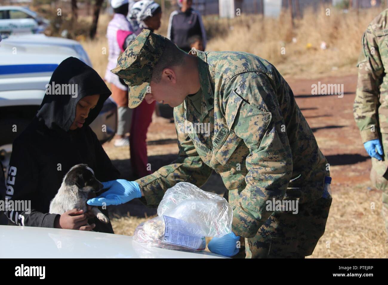 Sgt. Alex Vanlieshout, 3rd Battalion, 25th Marines provides food for a puppy while locals wait for free veterinary care during Mandela Day as part of Exercise Shared Accord 17 (SA17) in Postmasburg, South Africa, July 18, 2017. Mandela Day commemorates the lifetime of service Nelson Mandela gave to South Africa and the world, taking place every year on his birthday, with this years theme being, “action against poverty.” Stock Photo