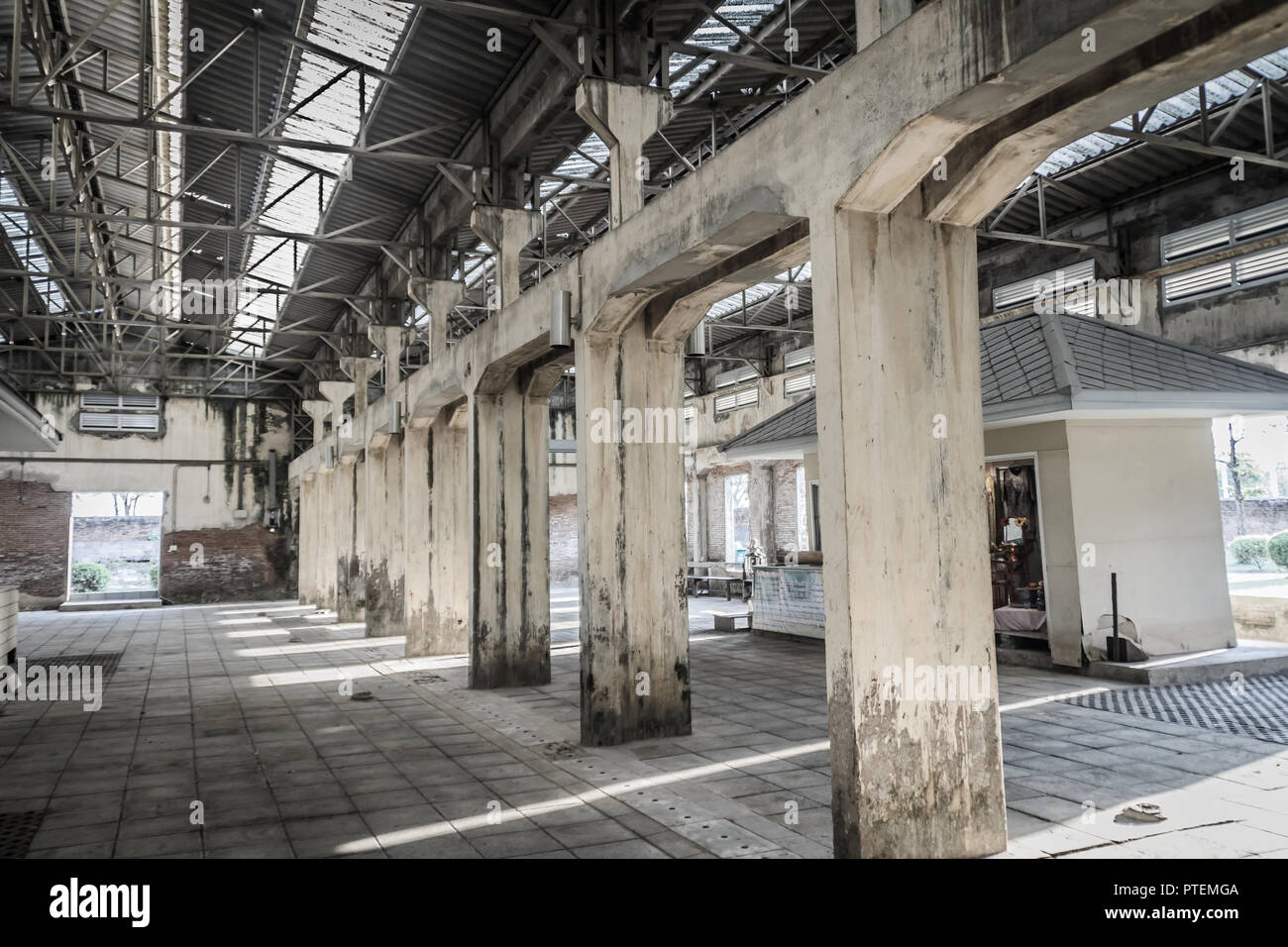 The ruins of an old abandoned factory. Perspective of abandoned warehouse from the inside with translucent roof and concrete structure. Stock Photo