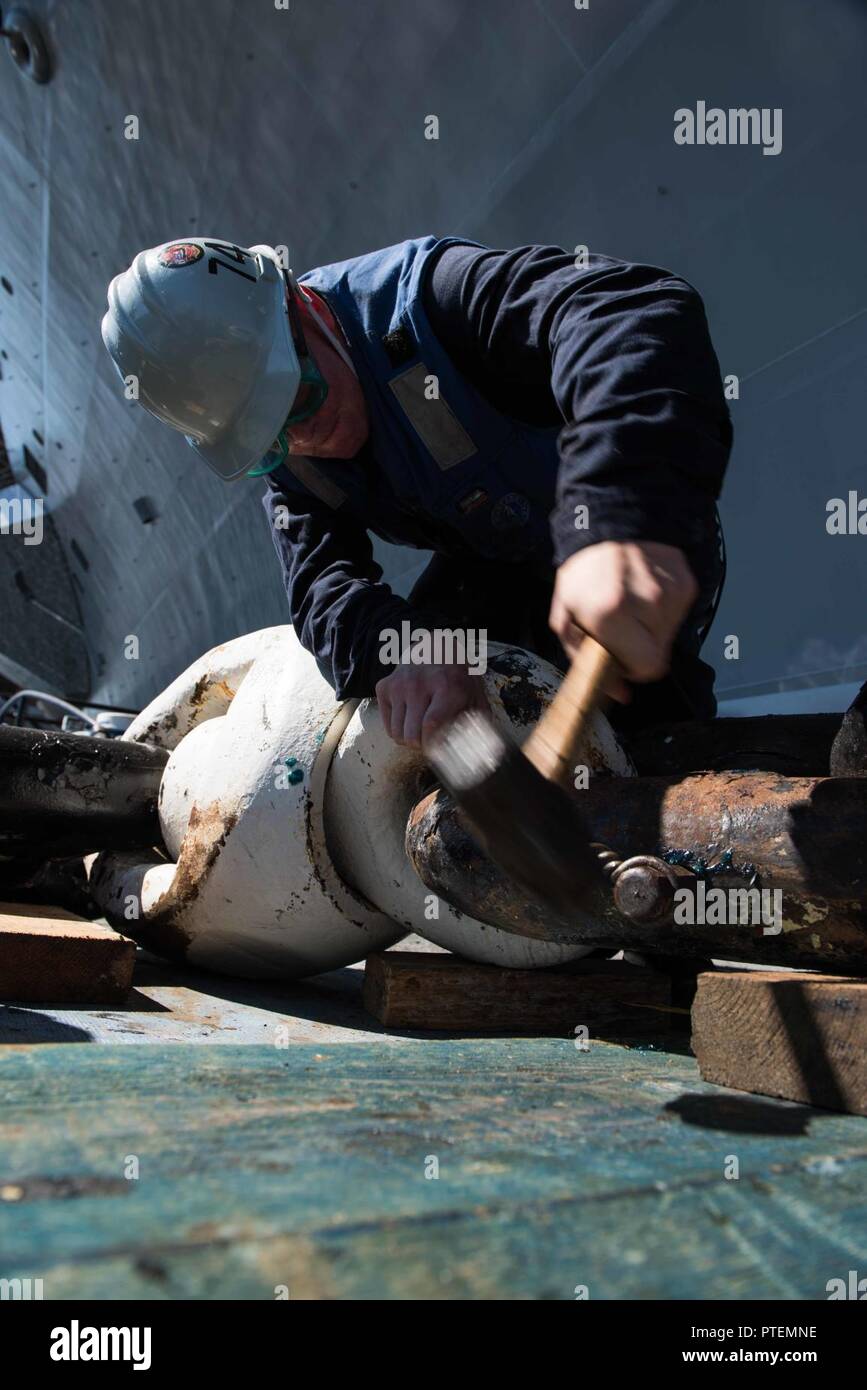 Washington (July 14, 2017) Seaman Aaron Miller, from Seattle, hammers a pin to lock a detachable link on USS John C. Stennis' (CVN 74) anchor chain into place. John C. Stennis is conducting a planned incremental availability (PIA) at Puget Sound Naval Shipyard and Intermediate Maintenance Facility, during which the ship is undergoing scheduled maintenance and upgrades. Stock Photo