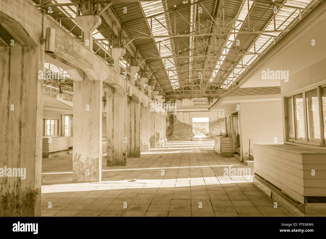 The ruins of an old abandoned factory. Perspective of abandoned warehouse from the inside with translucent roof and concrete structure. Stock Photo