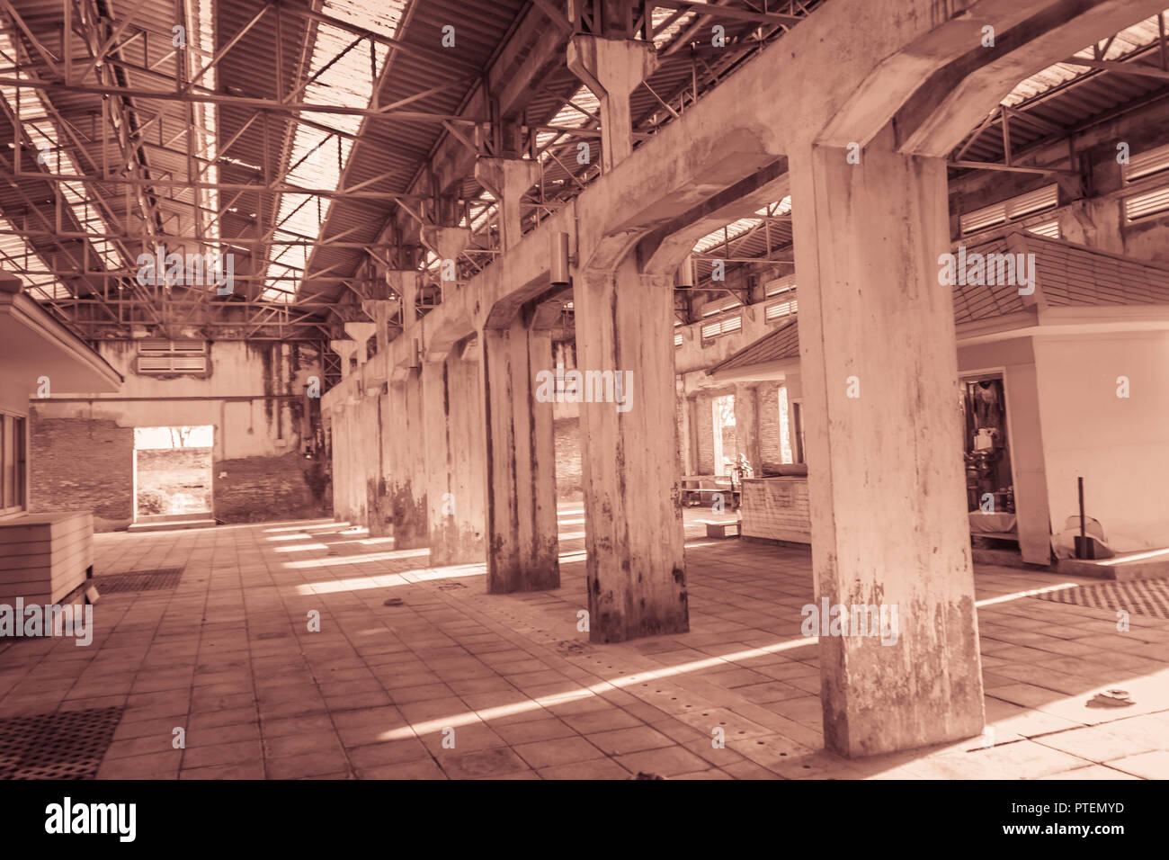 The ruins of an old abandoned factory. Perspective of abandoned warehouse from the inside with translucent roof and concrete structure. Stock Photo