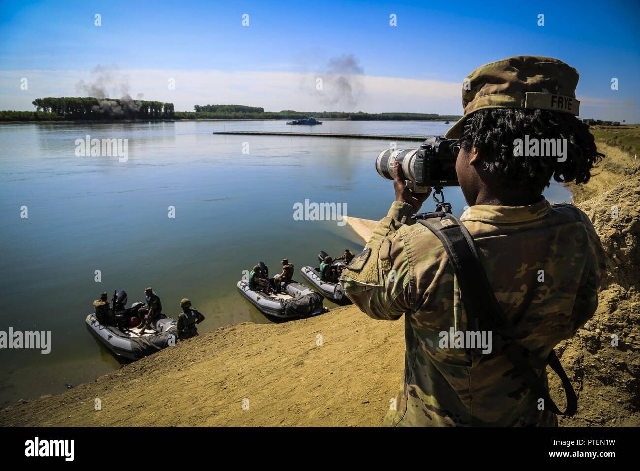 U.S. Army Private First Class Shekinah Frye, photographer assigned to 55th Signal Company (Combat Camera), documents a river crossing exercise during Saber Guardian 17 over the Danube River, Bordusani, Romania, July 15, 2017. Saber Guardian is a U.S. Army Europe-led multinational exercise that spans across Bulgaria, Hungary and Romania with more than 25,000 service members from 22 allied and partner nations. Stock Photo