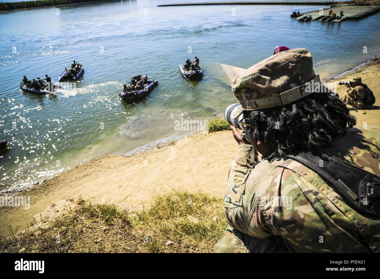 U.S. Army Pfc. Shekinah Frye, photographer assigned to 55th Signal Company (Combat Camera), documents a river crossing exercise during Saber Guardian 17 over the Danube River, Bordusani, Romania, July 15, 2017. Saber Guardian is a U.S. Army Europe-led multinational exercise that spans across Bulgaria, Hungary and Romania with more than 25,000 service members from 22 allied and partner nations. Stock Photo