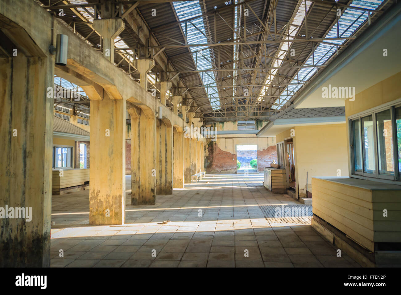 The ruins of an old abandoned factory. Perspective of abandoned warehouse from the inside with translucent roof and concrete structure. Stock Photo
