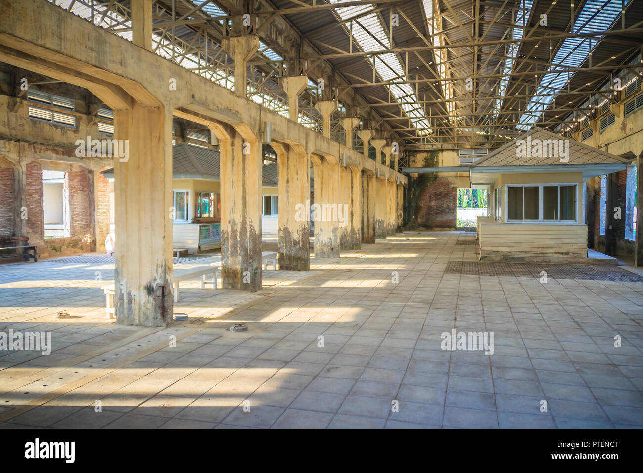 The ruins of an old abandoned factory. Perspective of abandoned warehouse from the inside with translucent roof and concrete structure. Stock Photo