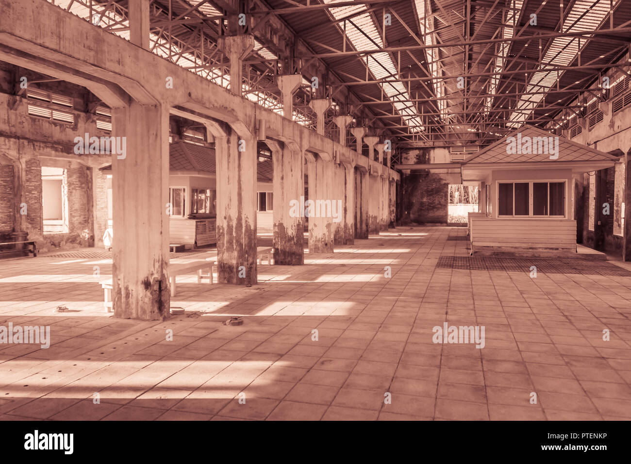 The ruins of an old abandoned factory. Perspective of abandoned warehouse from the inside with translucent roof and concrete structure. Stock Photo