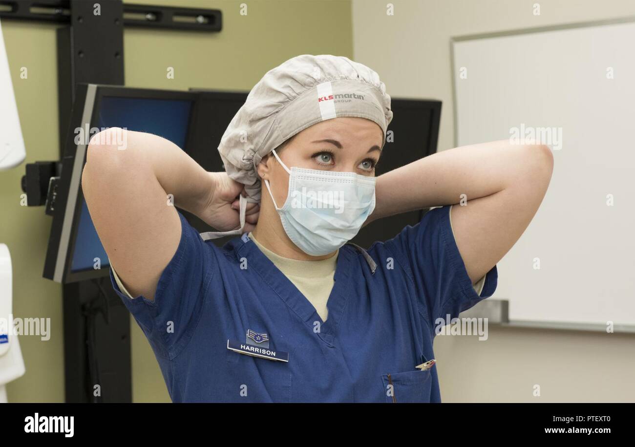 U.S. Air Force Senior Airman Dannie Harrison, 60th Dental Squadron, David  Grant USAF Medical Center, ties on a surgical cap and mask in preparation  to perform a clinical procedure at Travis Air