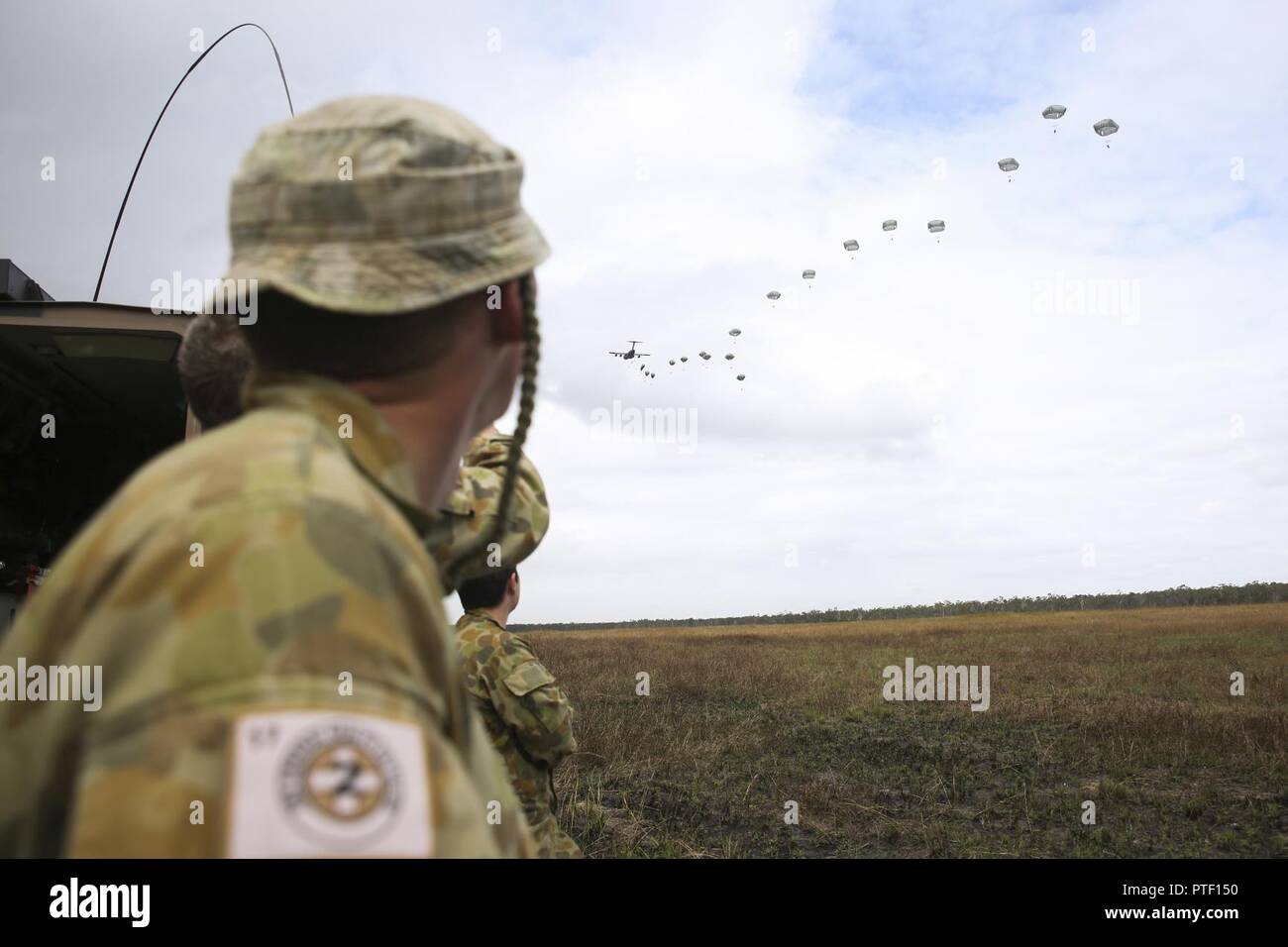 Australian Army Pvt. Jeremmy Bates, a medical technician with 2nd General Health Battalion, 17th Combat Service Support Brigade, watches as combined coalition forces parachute out of a C-17 Globemaster July 13, 2017 at Drop Zone Kapyong, Williamson Airfield, Shoalwater Bay Training Area, Queensland, Australia. Combined coalition forces from the United States and Canadian militaries conducted a small-scale tactical operation during Talisman Saber 17. Exercises like Talisman Saber provide effective and intense training to ensure our forces are capable, interoperable, deployable on short notice a Stock Photo