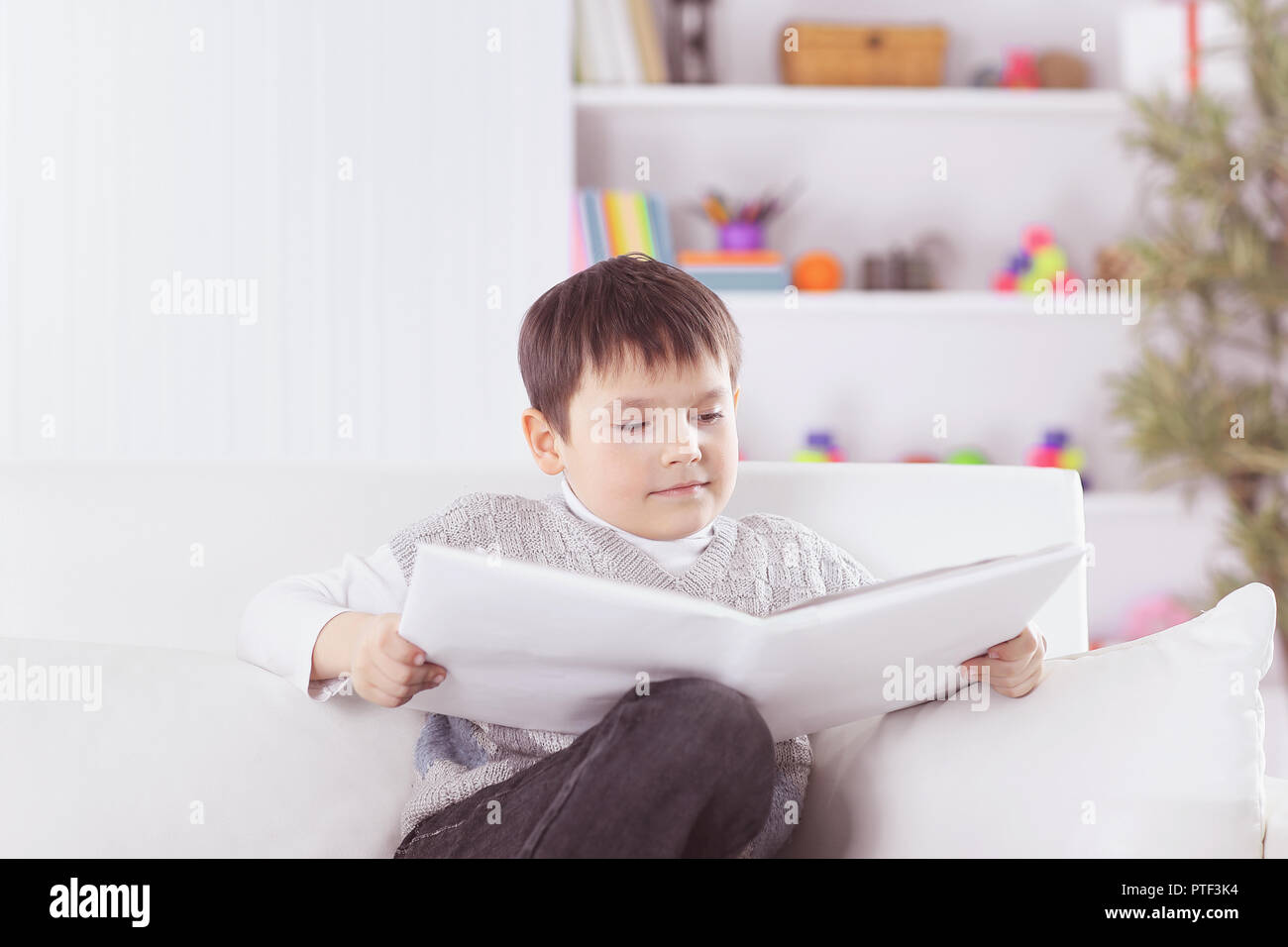 preschooler reading a book on the couch in the nursery Stock Photo Alamy