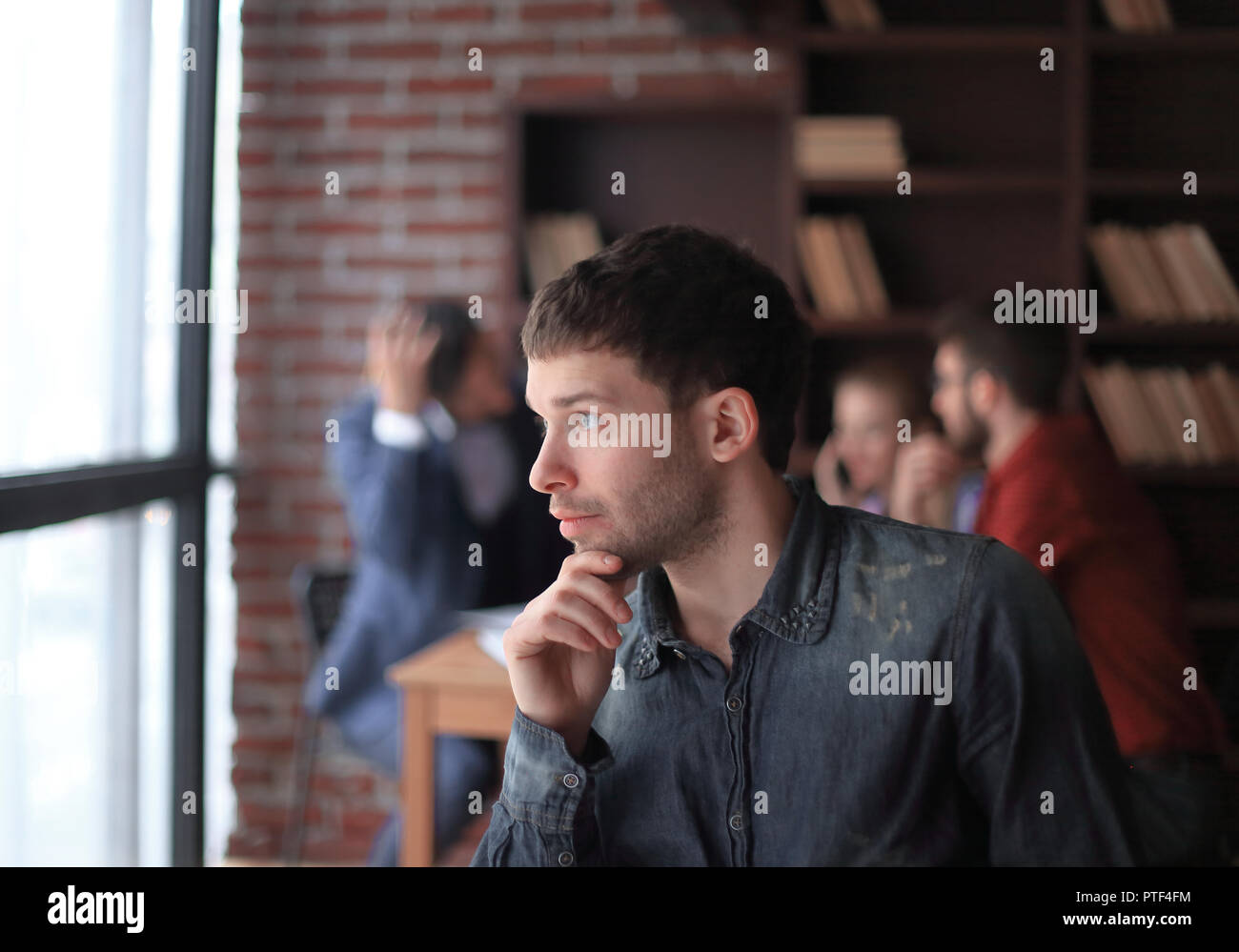 pensive young designer looking out the office window. Stock Photo
