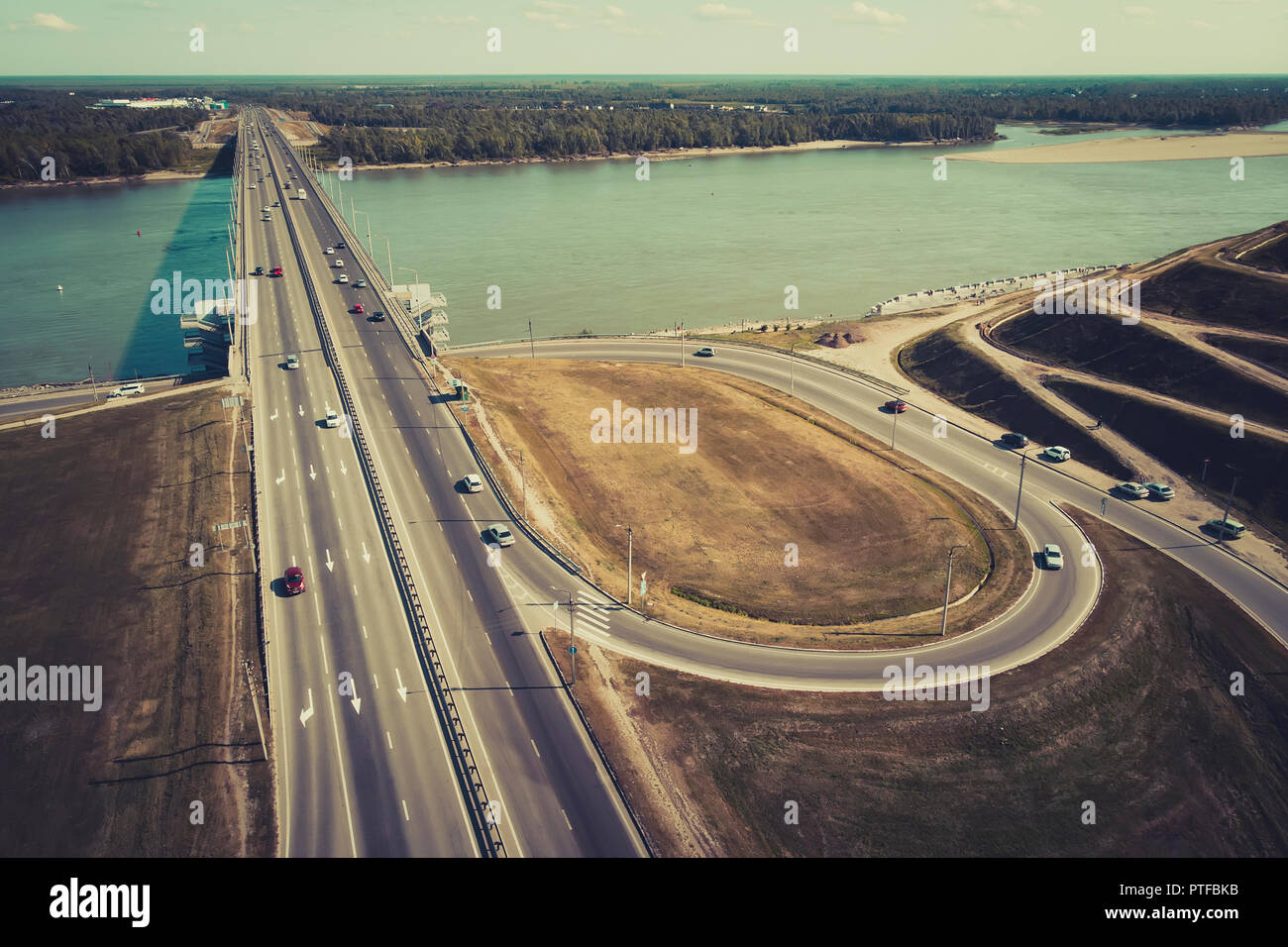 A view to the well-engireed city bridge and road interchange. A straight line of a well-built highway across the river banks and approach to it. City  Stock Photo