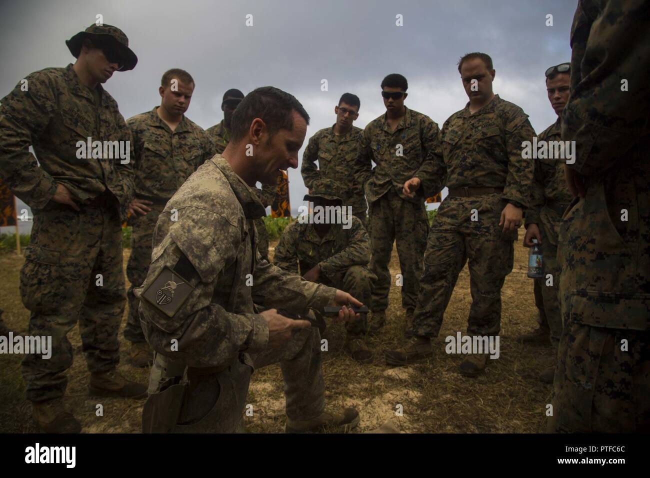 U.S. Marines with 3rd Battalion 4th Marines attached to Task Force Koa Moana 17, gather around New Zealand Army Sgt. Maj. Paul Buckley as he explains the glock 17 weapon system during Exercise TAFAKULA, on Tongatapu Island, Tonga, July 21, 2017. Exercise TAFAKULA is designed to strengthen the military-to-military, and community relations between Tonga’s His Majesty’s Armed Forces, French Army of New Caledonia, New Zealand Defense Force, and the United States Armed Forces. Stock Photo