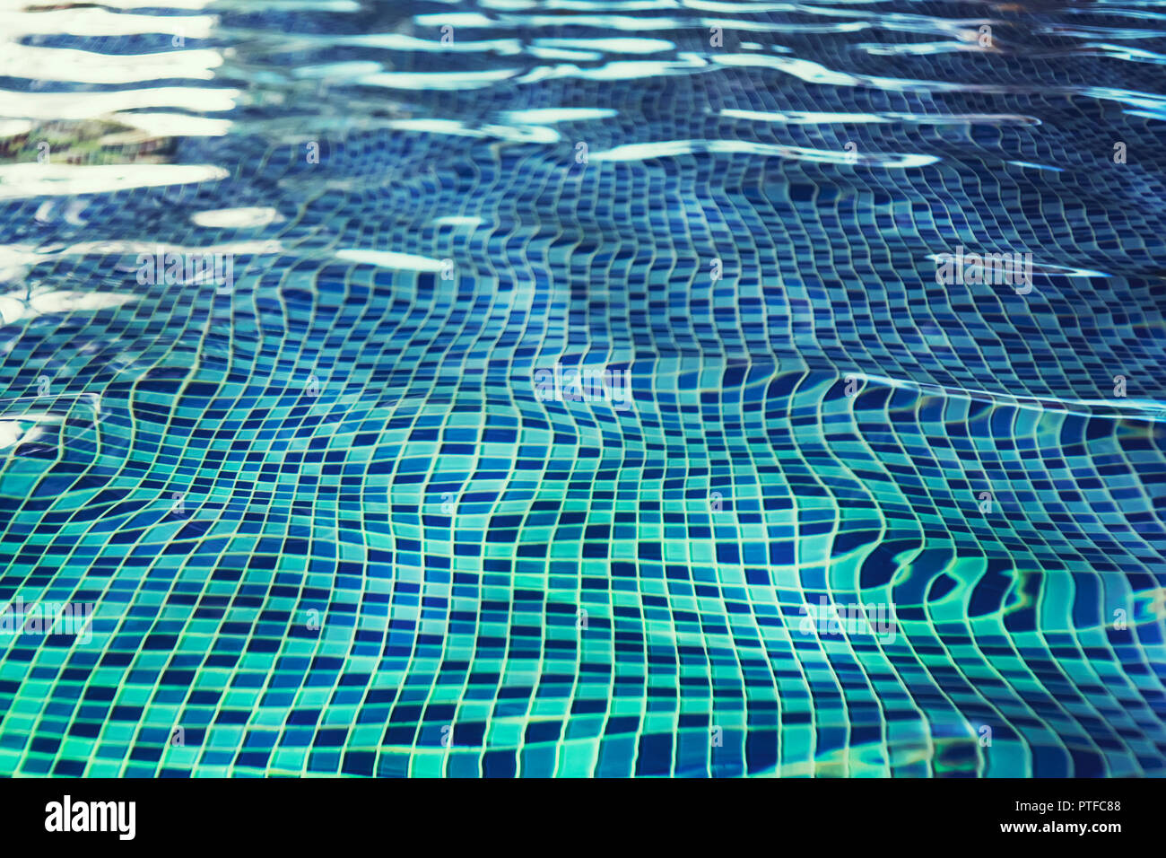 A fish eye effect of indoor pool rippling water at the blue-tiled mosaic floor. Waving of clean water in swimming pool with tiled floor. Swinging of w Stock Photo