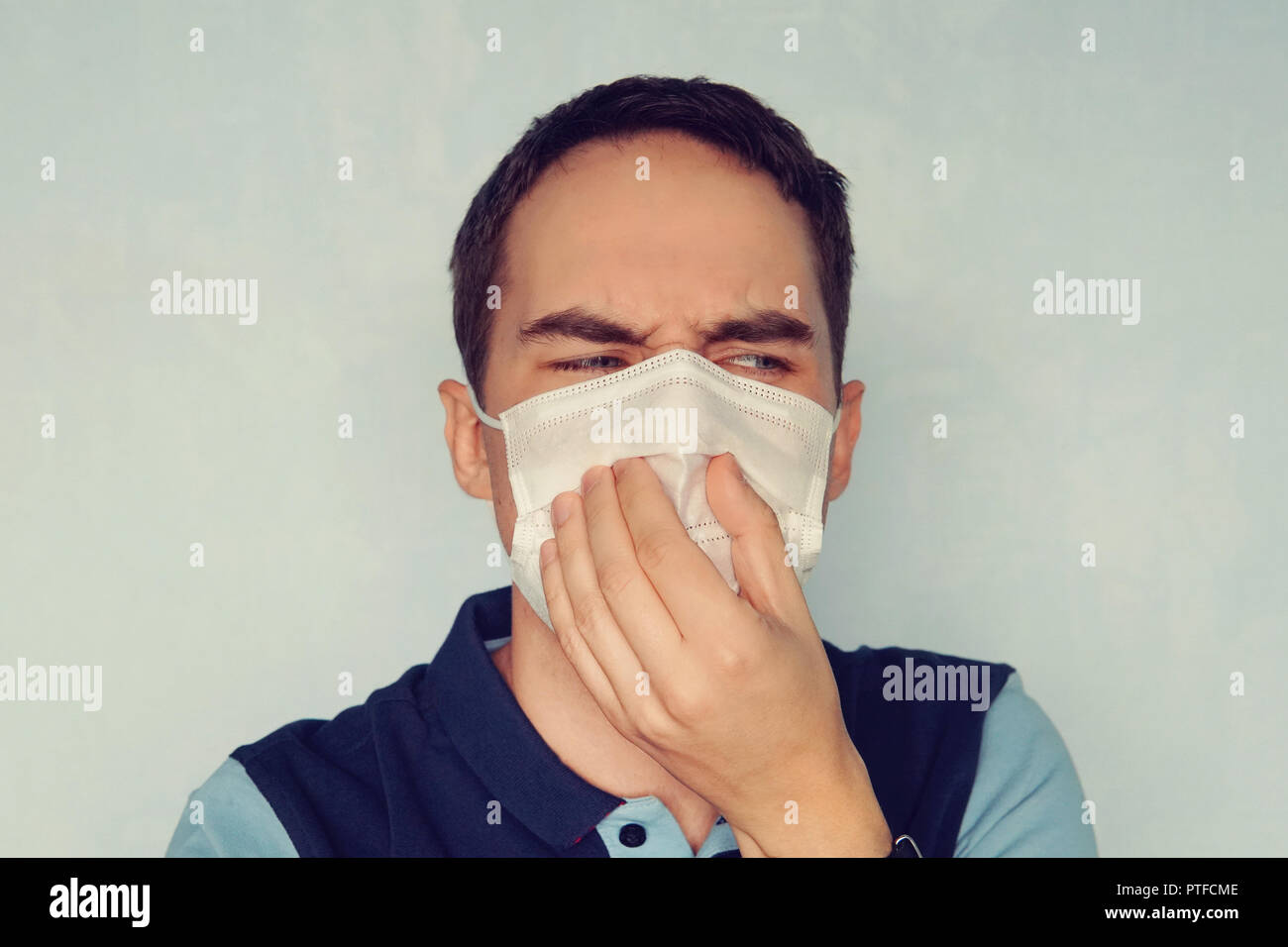 Man closes his mouth and nose from bad smell or stinky gas bad ecology. The concept of gas contamination and dust. harm to health, health damage, dama Stock Photo