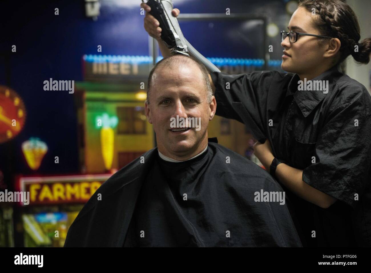 Wash. (July 19, 2017) Ship's Serviceman Seaman Stephanie Santana, from Hialeah, Fla., gives Capt. Scott Miller, executive officer of the aircraft carrier USS John C. Stennis (CVN 74), the first hair cut in the ship’s newly remodeled barber shop since the beginning of the ship’s planned incremental availability (PIA). Services such as the barber shop, coffee shop, ship’s store and galleys are returning for crew use for the first time since closing at the beginning of PIA. John C. Stennis is conducting a PIA at Puget Sound Naval Shipyard and Intermediate Maintenance Facility, during which the sh Stock Photo