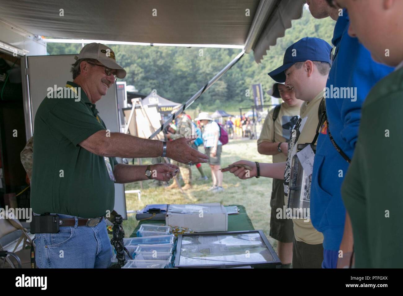 Dave Simmons, a Vietnam Veteran and West Virginia State Council President, sells historical war items to a Boy Scout at the West Virginia State Council Vietnam Veterans of America exhibit at the military exhibition site during the 2017 National Jamboree held at Summit Bechtel Reserve near Glen Jean, W.Va., July 21, 2017. The 2017 National Jamboree is being attended by 30,000 Boy Scouts, troop leaders, volunteers and professional staff members, as well as more than 15,000 visitors. Approximately 1,200 military members from the Department of Defense and the U.S. Coast Guard are providing logisti Stock Photo