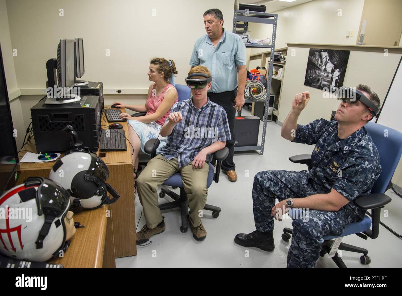 Rachel Meyerhofer and Jeffrey Banghart, student interns temporarily assigned to Naval Surface Warfare Center, Carderock Division's Disruptive Technology Laboratory (DTL) under the Naval Research Enterprise Internship Program (NREIP), respectively, work with Lt. Brian Hart under the supervision of DTL deputy director and NREIP mentor Harry Whittaker to stream video from one Microsoft Hololens augmented reality heads-up display to another as part of a project they are working on for the next version of the Optionally Manned Technology Demonstrator (OMTD) in West Bethesda, Md., July 21. The DTL a Stock Photo