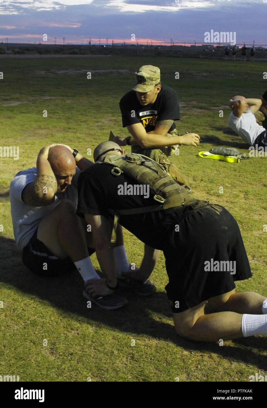 Army Staff Sgt. Travis Browning, center, cadre, 1st Armored Division Iron Training Detachment, grades an Airman on his sit-ups as a Soldier holds his feet during the Ranger Physical Assessment at the Ranger Assessment Course at Fort Bliss, Texas July 10, 2017. U.S. Army Stock Photo