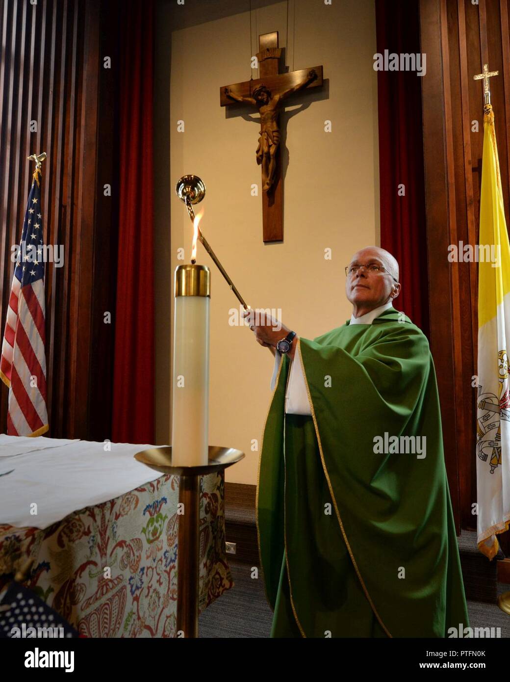 U.S. Air Force Maj. (Father) Tom Gills, 88th Air Base Wing Chaplain Service’s branch chief of Parish Ministries, lights a candle -symbolic for the light of the world-, prior to a Catholic mass service held at the Kittyhawk chapel on Wright-Patterson Air Force Base, Ohio, July 12, 2017. The Air Force Chaplain Corps ministry expands beyond providing religious ministry for those of like faith and practice to facilitating all religious practices and caring for every Airman, including those who observe no religion at all. Stock Photo