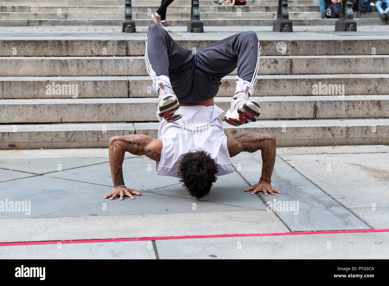 STREET PERFORMER. An acrobatic breakdancing busker doing a handstand in front of the main branch of the NY Public Library on Fifth Ave. in Manhattan. Stock Photo