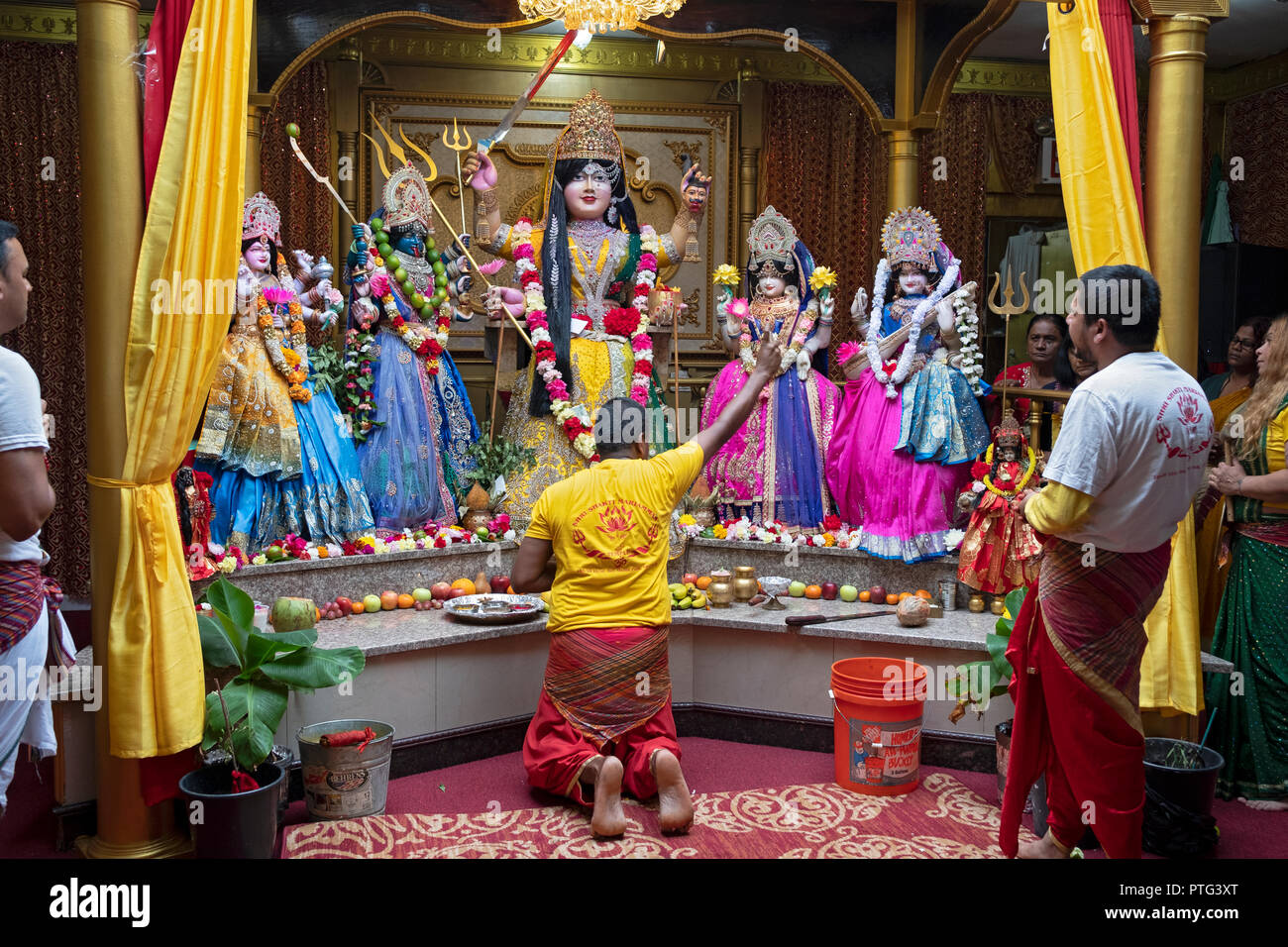 A worshipper making offering to the deities at a Hindu Mandir (temple) in Richmond Hill, Queens, New York. Stock Photo