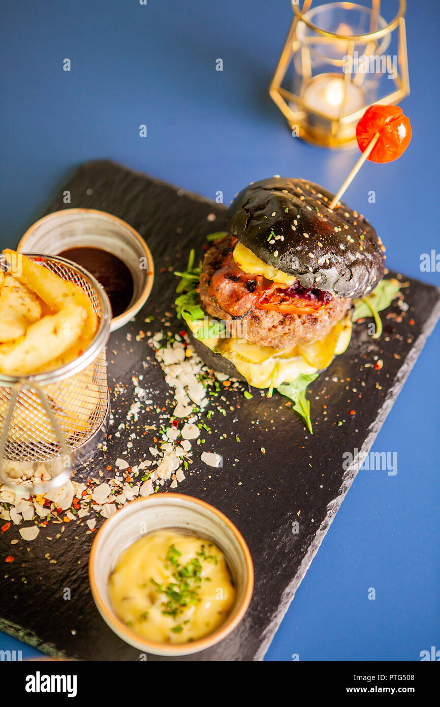 Jucy burger with french fries and soia sos on restaurant table. Tasty food Stock Photo
