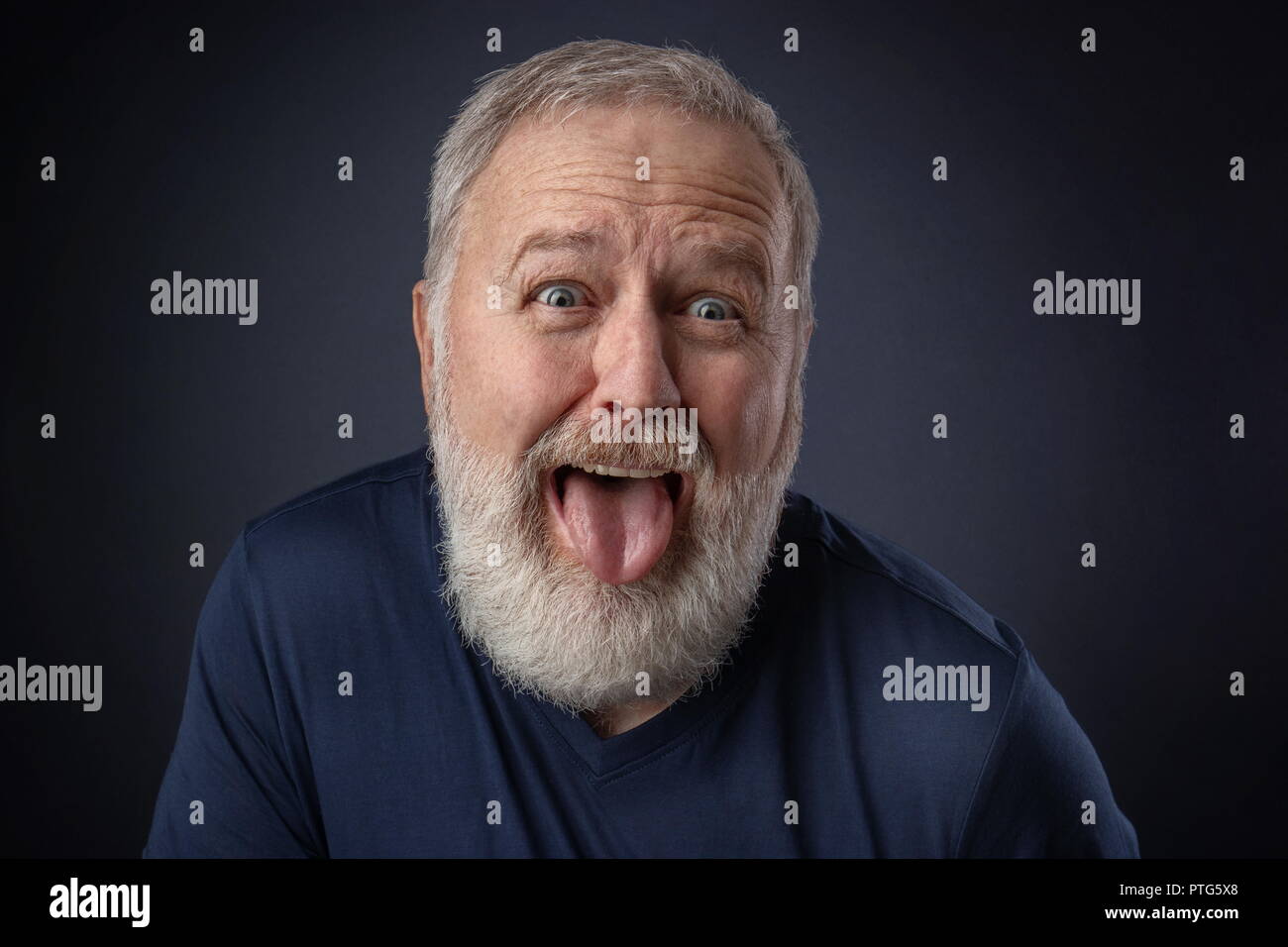 Portrait of an old man making a nasty grimace and pulling the tongue out Stock Photo