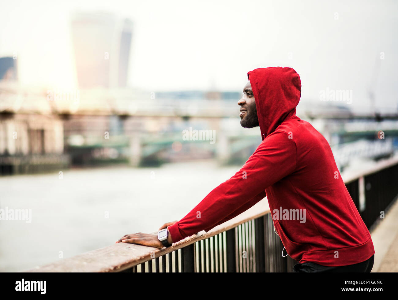 Young sporty black man runner on the bridge outside in a city, resting. Stock Photo