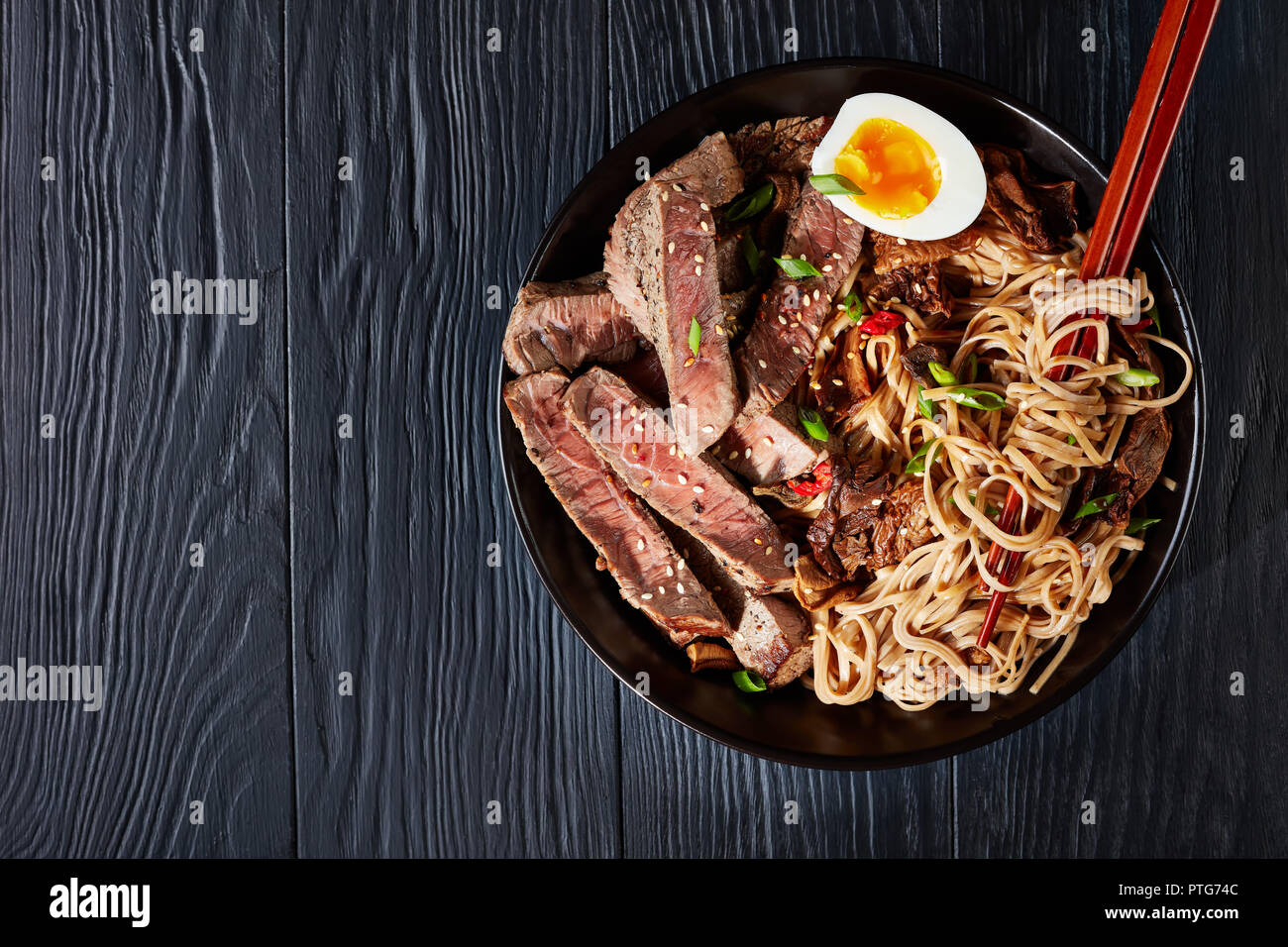 black bowl of Soba noodles with sliced roast beef, shiitake mushrooms