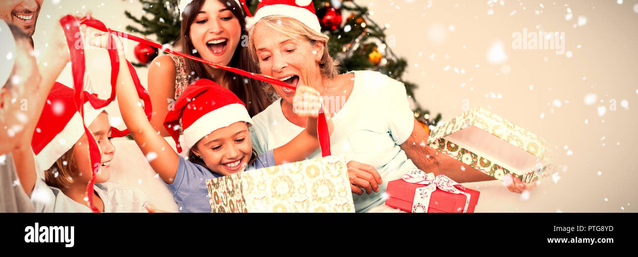 Composite image of happy family at christmas opening gifts together Stock Photo