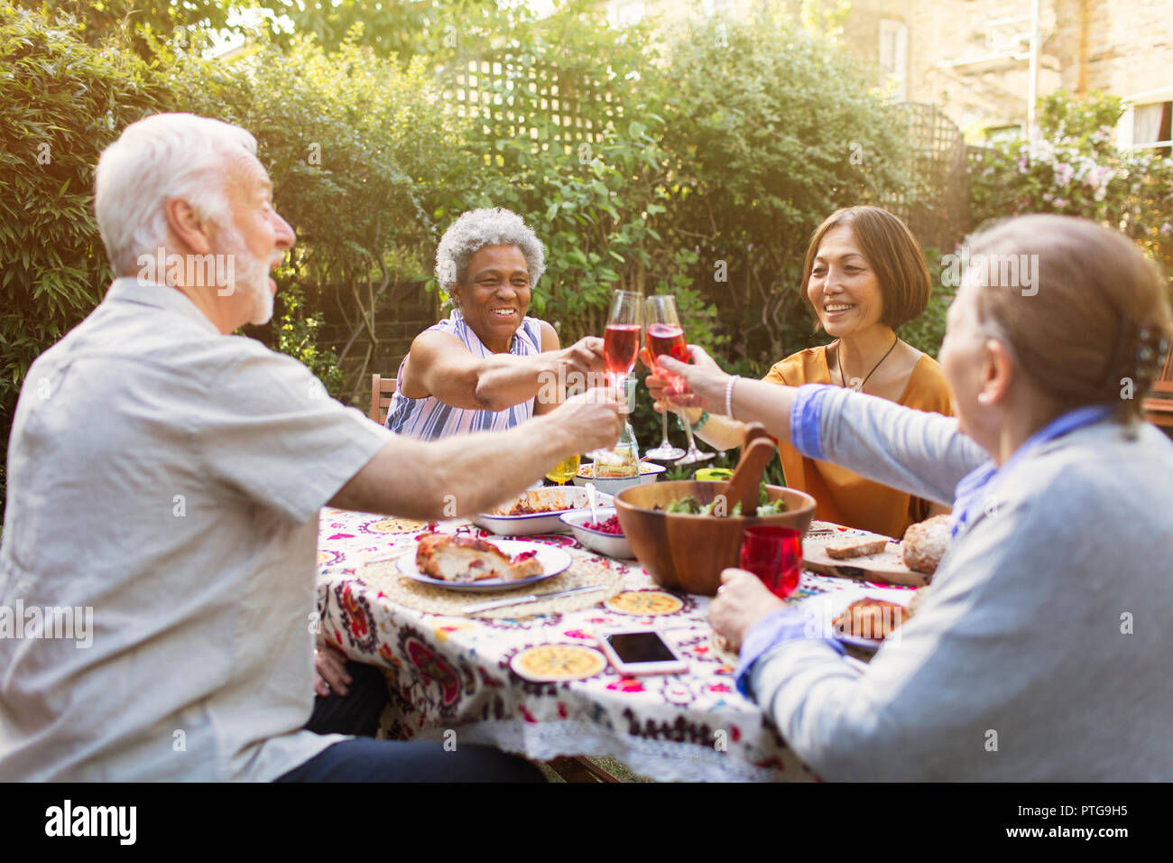 Active senior friends toasting rose wine glasses at garden party Stock Photo