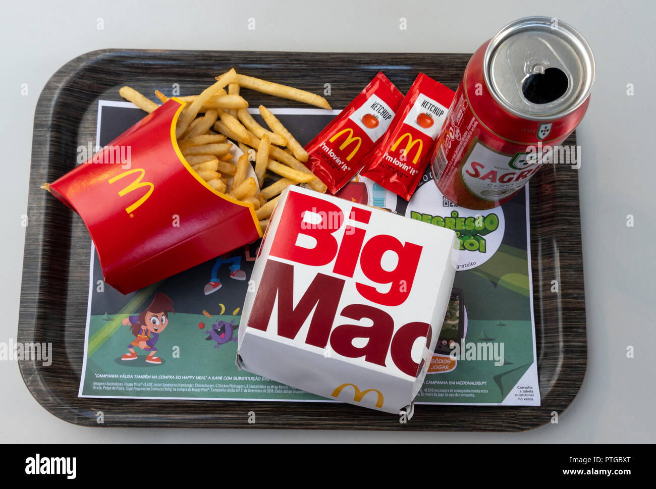 A Big Mac meal with fries, ketchup packets, and a beer in Lisbon, Portugal Stock Photo