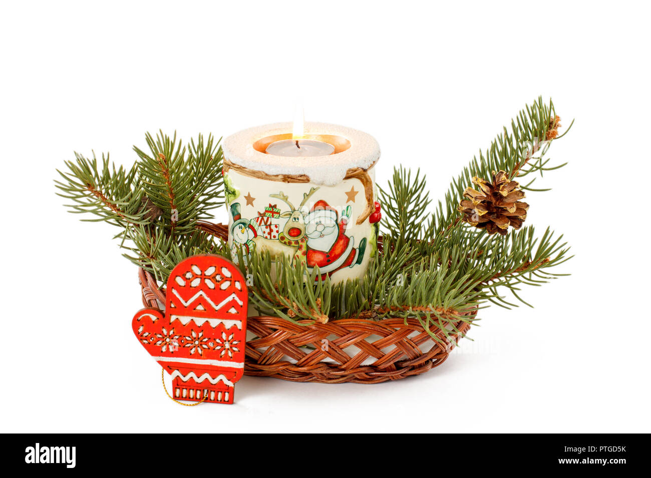 Burning candle, cone and natural fir tree branches in wicker basket ...
