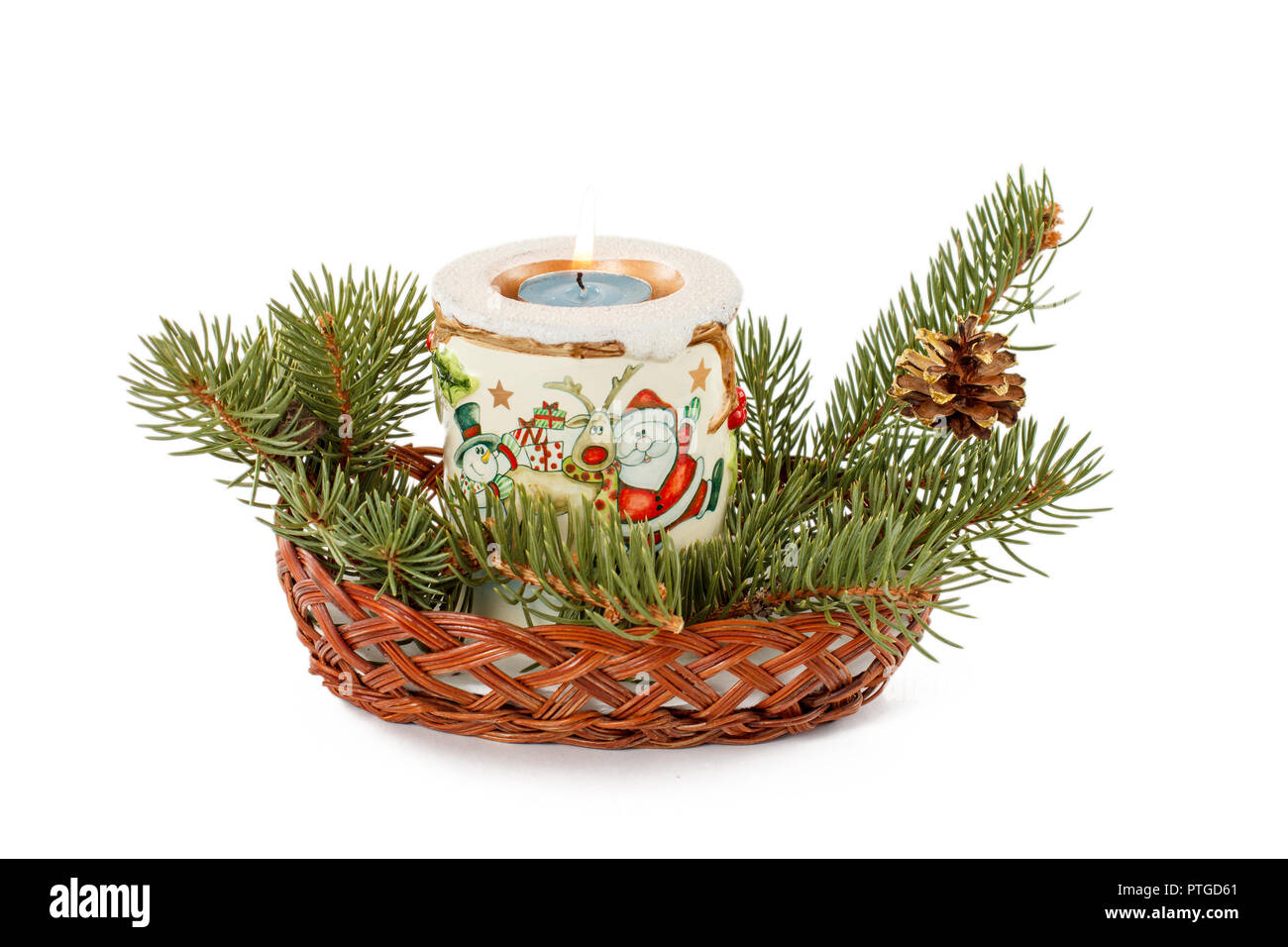 Burning candle, cone and natural fir tree branches in wicker basket ...