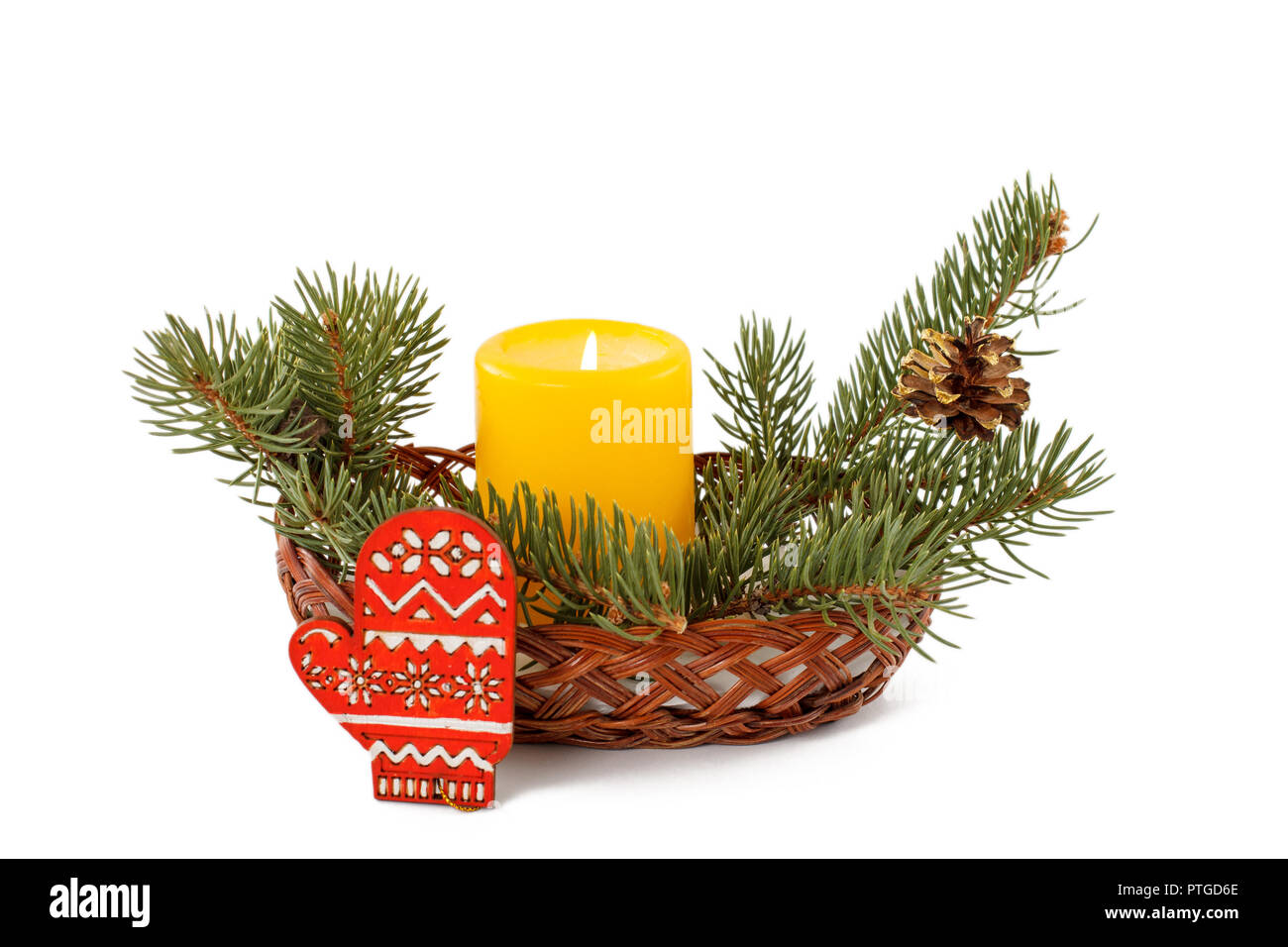 Burning candle, cone and natural fir tree branches in wicker basket ...