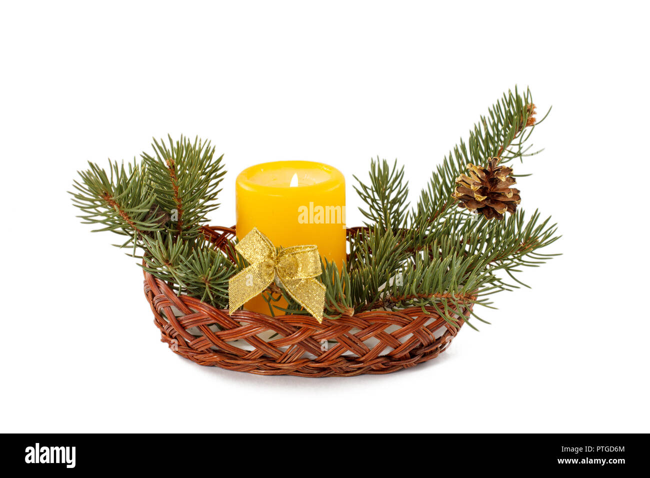 Burning candle, cone and natural fir tree branches in wicker basket ...