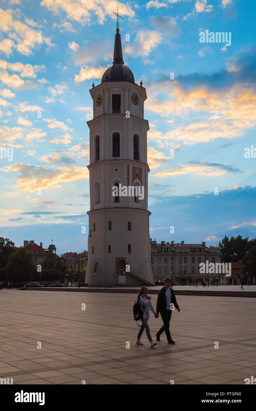 Bell tower Vilnius, view at dusk of a young couple walking through Cathedral Square with the 57m tall belfry tower behind them, Vilnius, Lithuania. Stock Photo