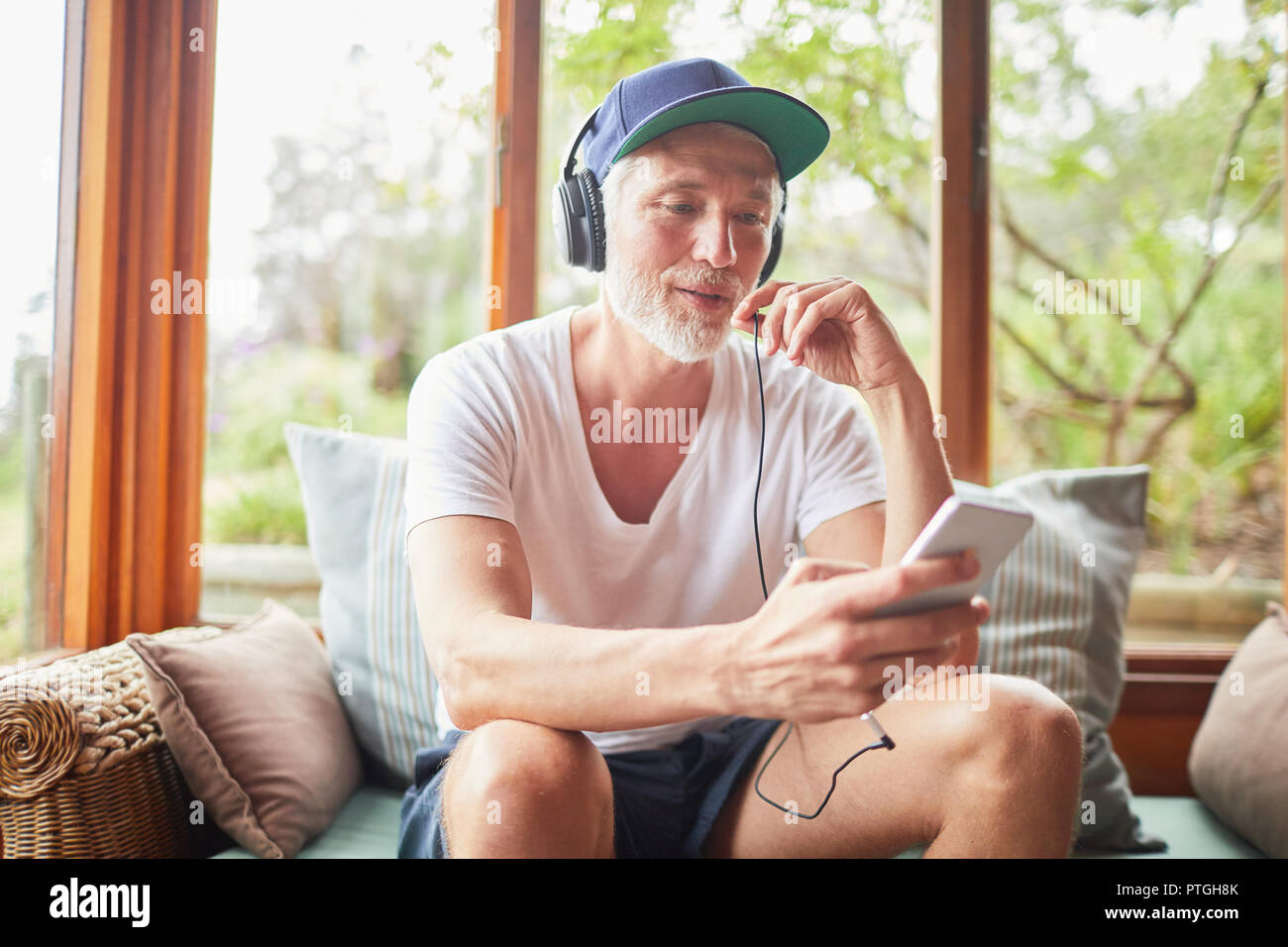 Man with headphones and mp3 player listening to music in living room Stock Photo