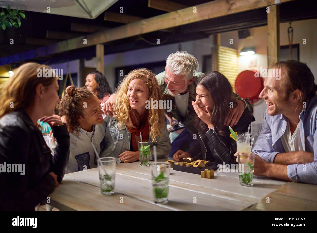 Friends hanging out, drinking on patio at night Stock Photo