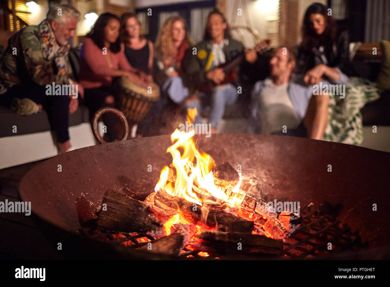 Friends hanging out, playing music on patio next to fire pit Stock Photo